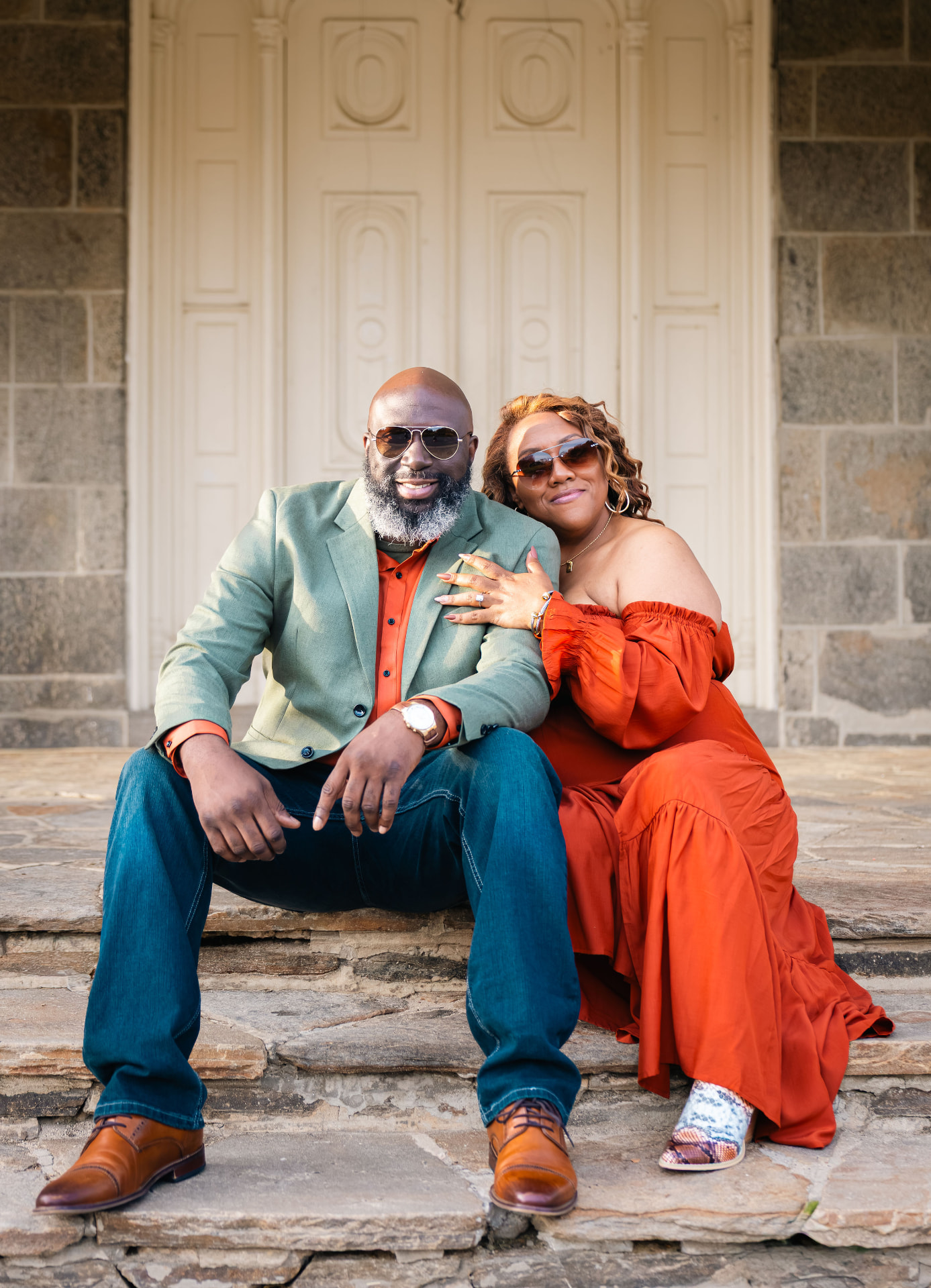 Nikki and Mike seated on stone steps in sage and rust