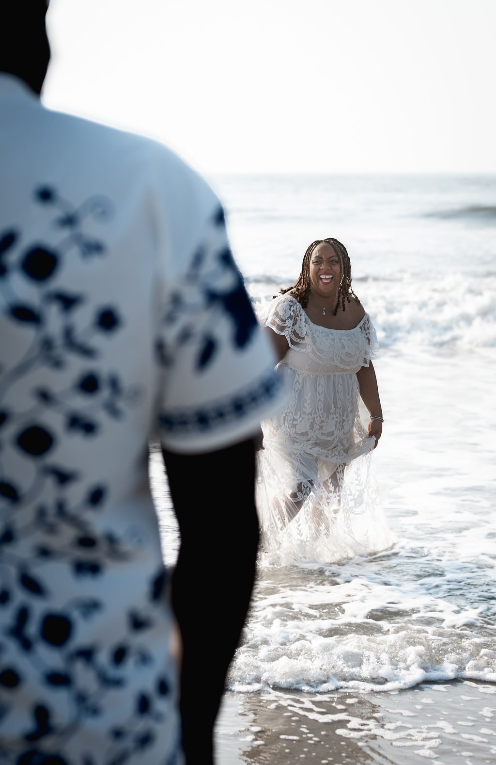 Nikki smiling as she walks through the waves in white lace
