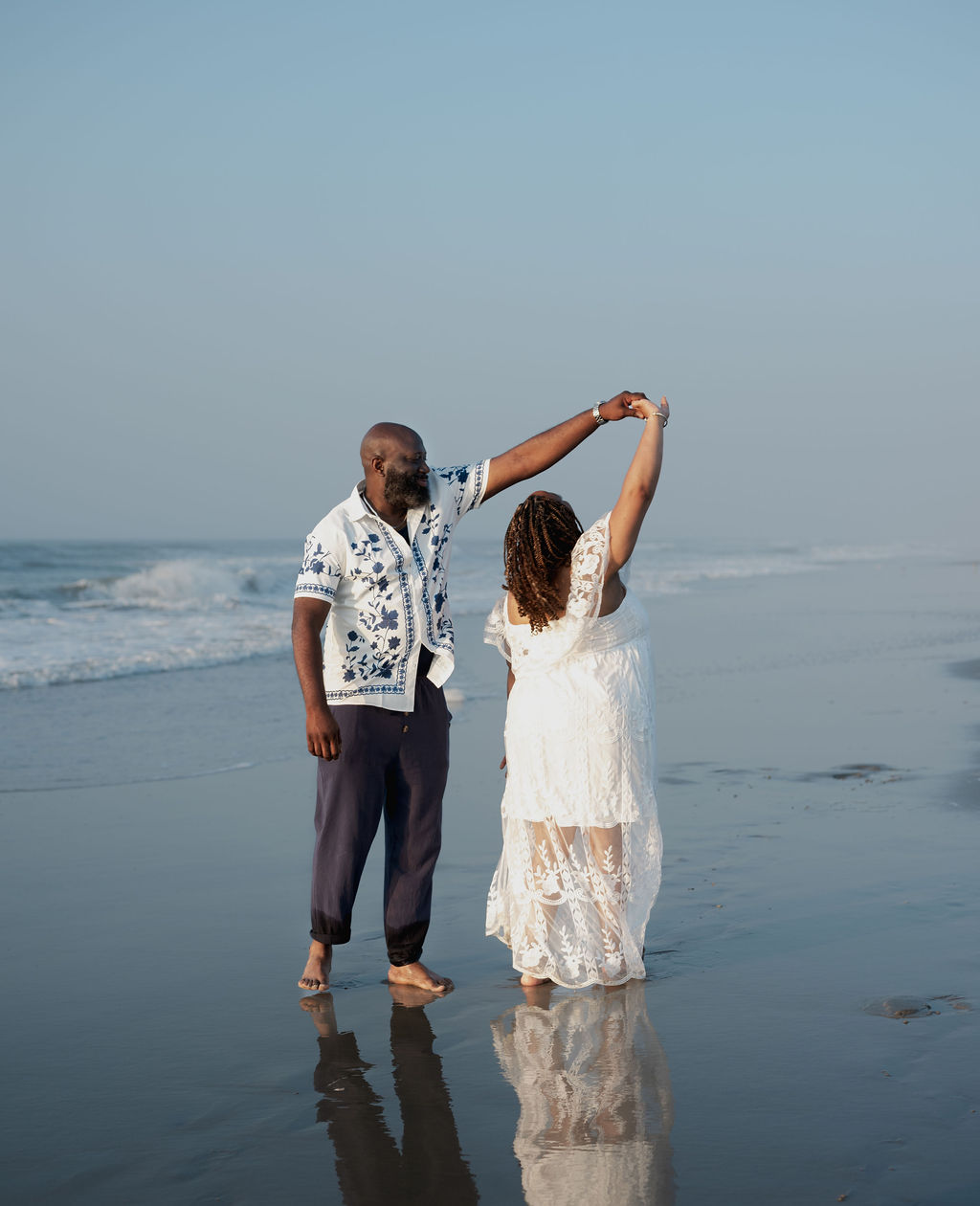 Mike twirling Nikki in the shallow surf at golden hour