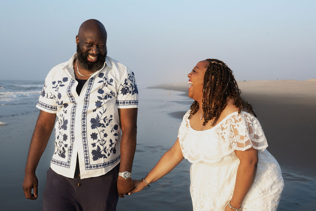 Nikki and Mike laughing together hand in hand on the beach