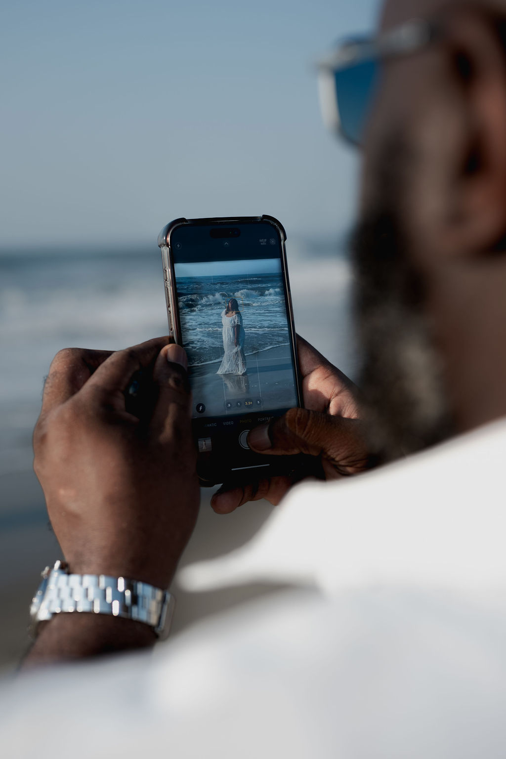 Mike photographing Nikki by the ocean on his phone
